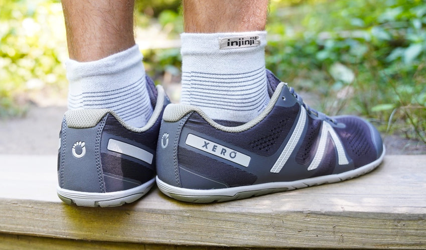 The feet and lower legs of an athlete wearing Injinji toe socks and Xero HFS Pewter shoes