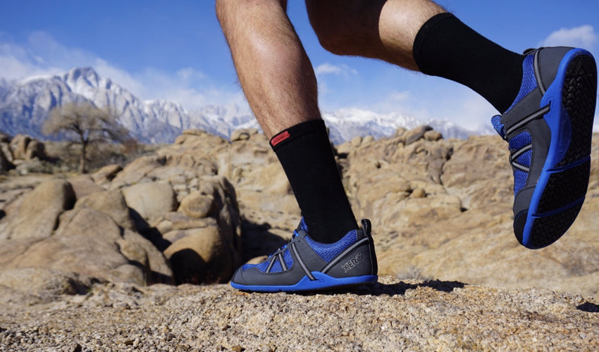 A trail runner in mid-stride wearing Xero Prio Lightning Blue athletic shoes