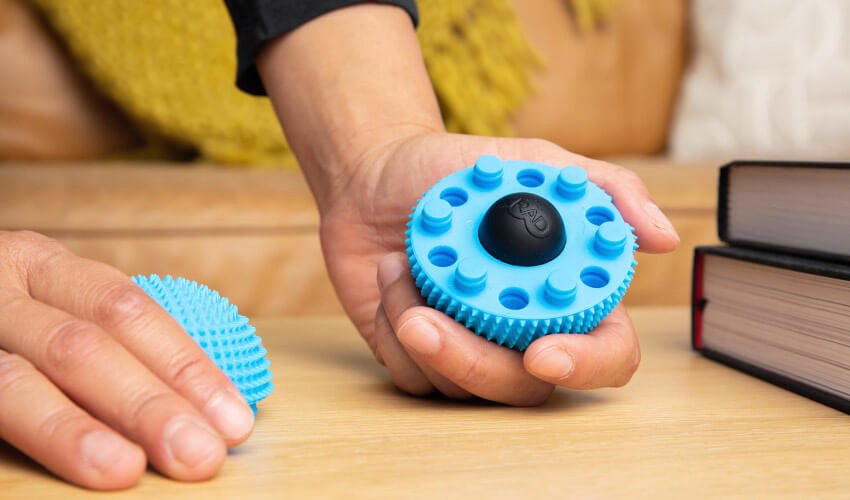 Person holding a Naboso Neuro Ball that has been split in two to reveal the bonus “Micro Round” contained within