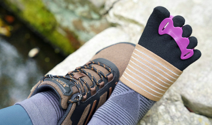 Over-the-shoulder view of a set of feet wearing Xero DayLite Hiker hiking boots, Correct Toes Plum toe spacers, Injinji toe socks, and Strutz foot pads