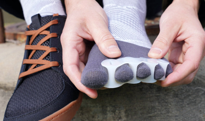 Head-on view of a person putting on a Correct Toes Original toe spacer over Injinji toe socks