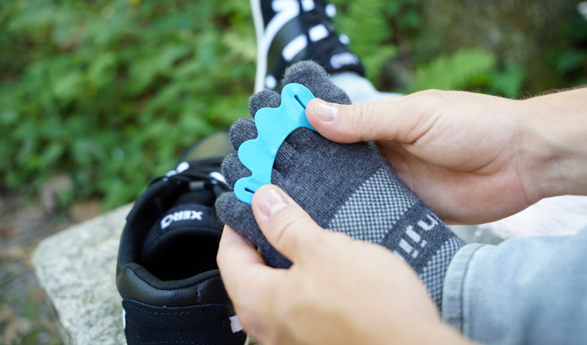 Over-the-shoulder shot of a person putting on a Correct Toes Aqua toe spacer