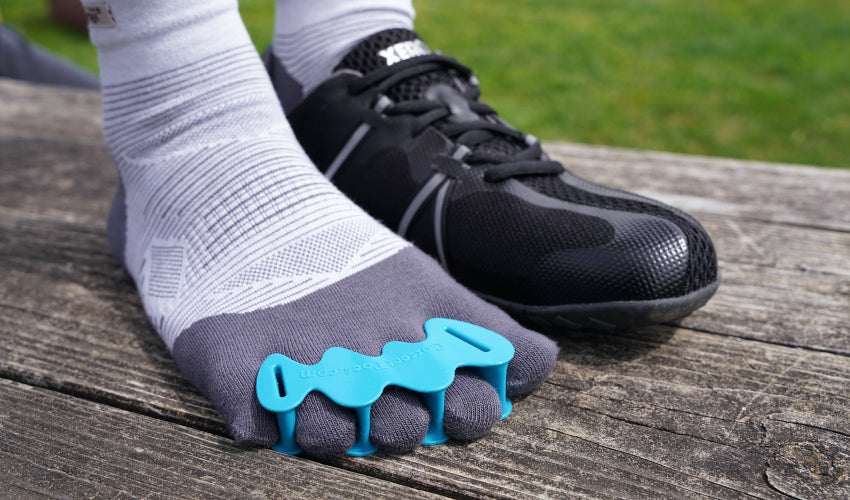 Close-up of a foot wearing a Correct Toes Aqua toe spacer over Injinji toe socks