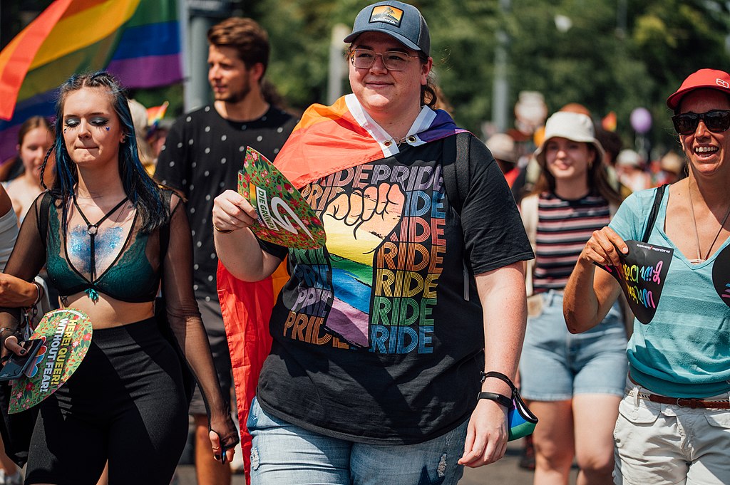 Pride parade attendee with a colorful Pried t-shirt and rainbow flag