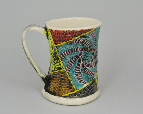 Handmade mug with a patchwork lace pattern in multiple colours.