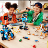 Shows young teens building something at a table in a room.