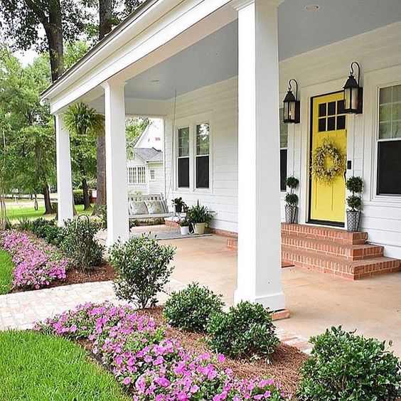 A yellow Therma-tru door featuring exterior columns and accompanied by a garden