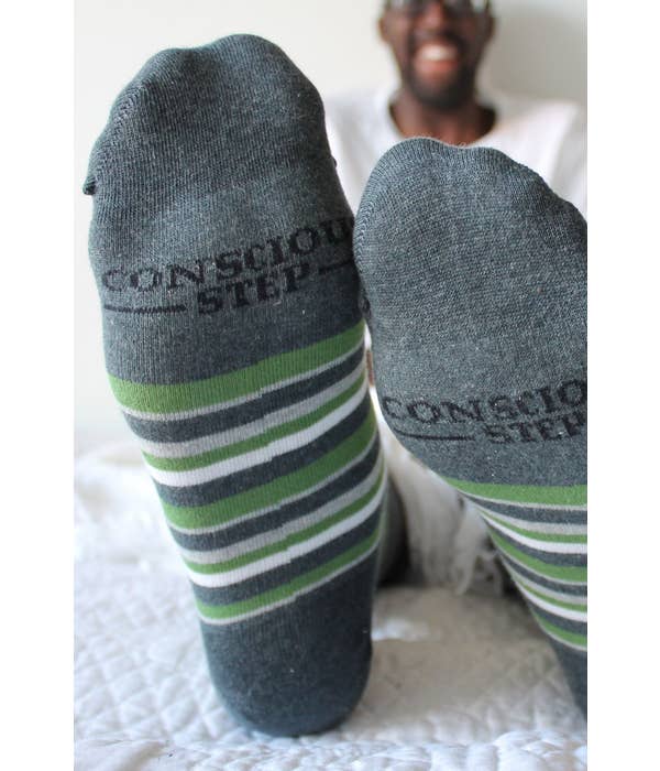 Conscious Step socks are shown front and center in this photo with the smiling face of the foot's owner shown in the blurred background. 