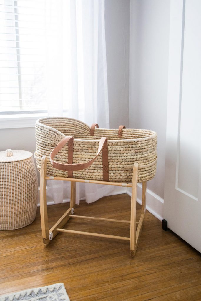 Gift an expecting mother with this fair trade, handcrafted moses basket. Shown here in a stand in a white room with white curtains. Her first Mother's Day experience will be a memorable one!