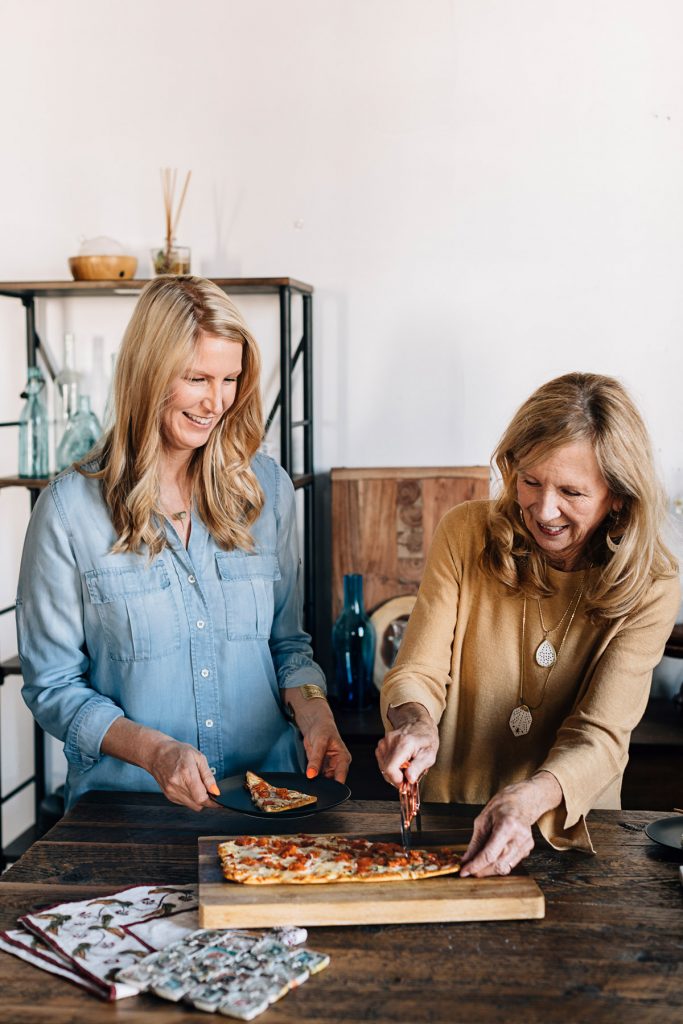Mother's Day experiences increase your giving impact! This mother-daughter pair are cutting into a pizza with the Bicycle Pizza Cutter. 