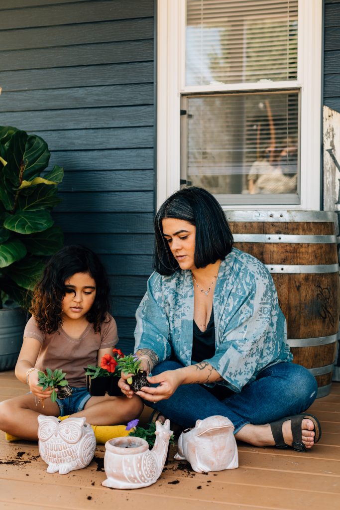 Terracotta planters in the shape of animals handcrafted by fair trade artisans are receiving plants from a little girl and her mother. Mother's Day experiences increase your giving impact for sure!