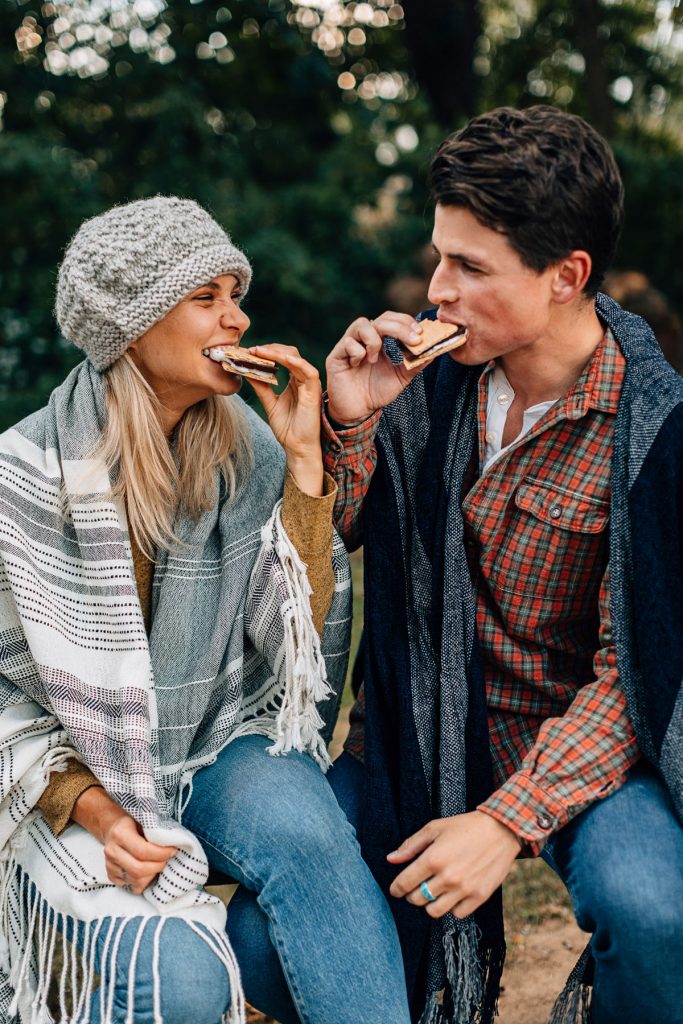 A sustainable Christmas gift idea: give experiences! Image shows two people enjoying s'mores together around a campfire. 