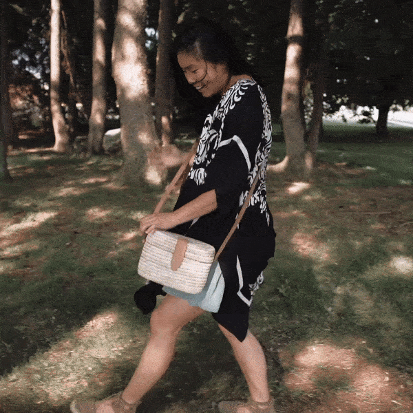 Model twirls in the black and white Light and Airy Topper with the Crossbody Woven Purse over her shoulder in this GIF. 