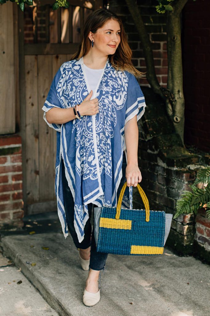 Model wears the Damask Print Wrap in this summer 2021 fashion trend. She appears to be walking with the wrap flowing around her with the Sunbeam Purse in her left hand. 