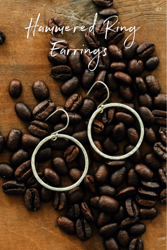 Hammered Ring Earrings from Ten Thousand Villages | Handmade fair trade jewelry by artisans of Bombolulu Workshops in Kenya. Earrings lay in scattered coffee beans. 