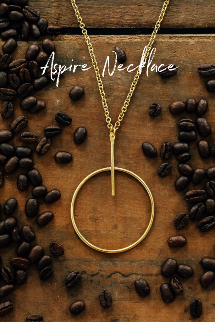 The Aspire Necklace from Ten Thousand Villages | Handmade fair trade jewelry by Bombolulu Workshop artisans in Kenyan lays in scattered coffee beans. 