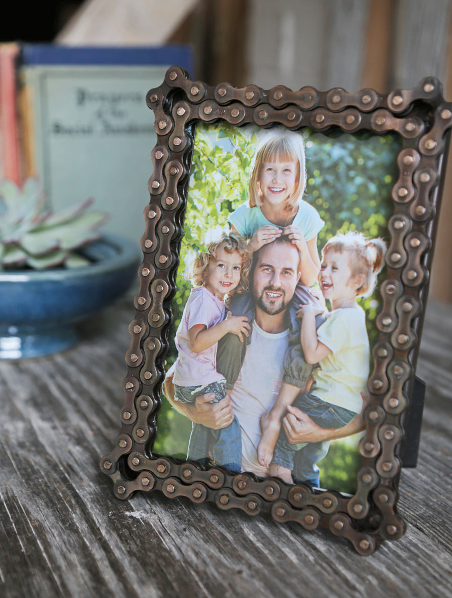 A 5x7 picture frame made of recycled bike chain shows a photo of a father and his three children. A great father's day gift for the cyclist or innovator!