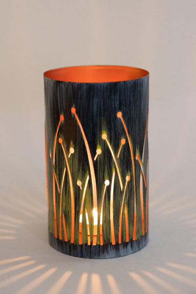 black metal candleholder with cutouts that look like grass blowing in the wind