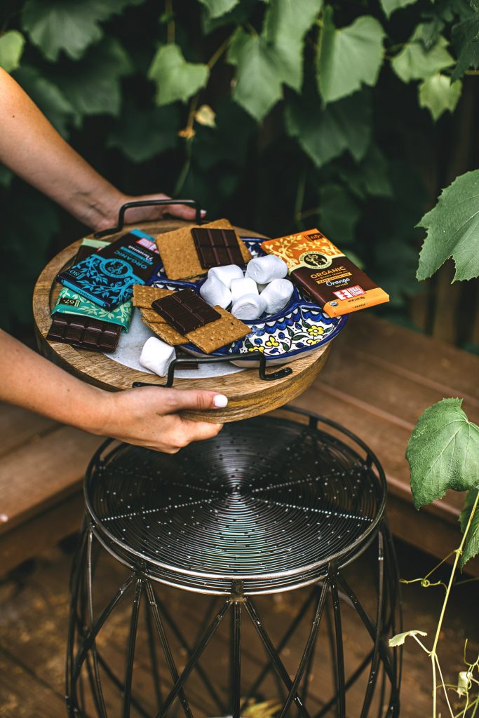 Not your average s'mores! Image shows a tray of s'mores fixings together being set down by a person whose arms and hands are in the frame. 