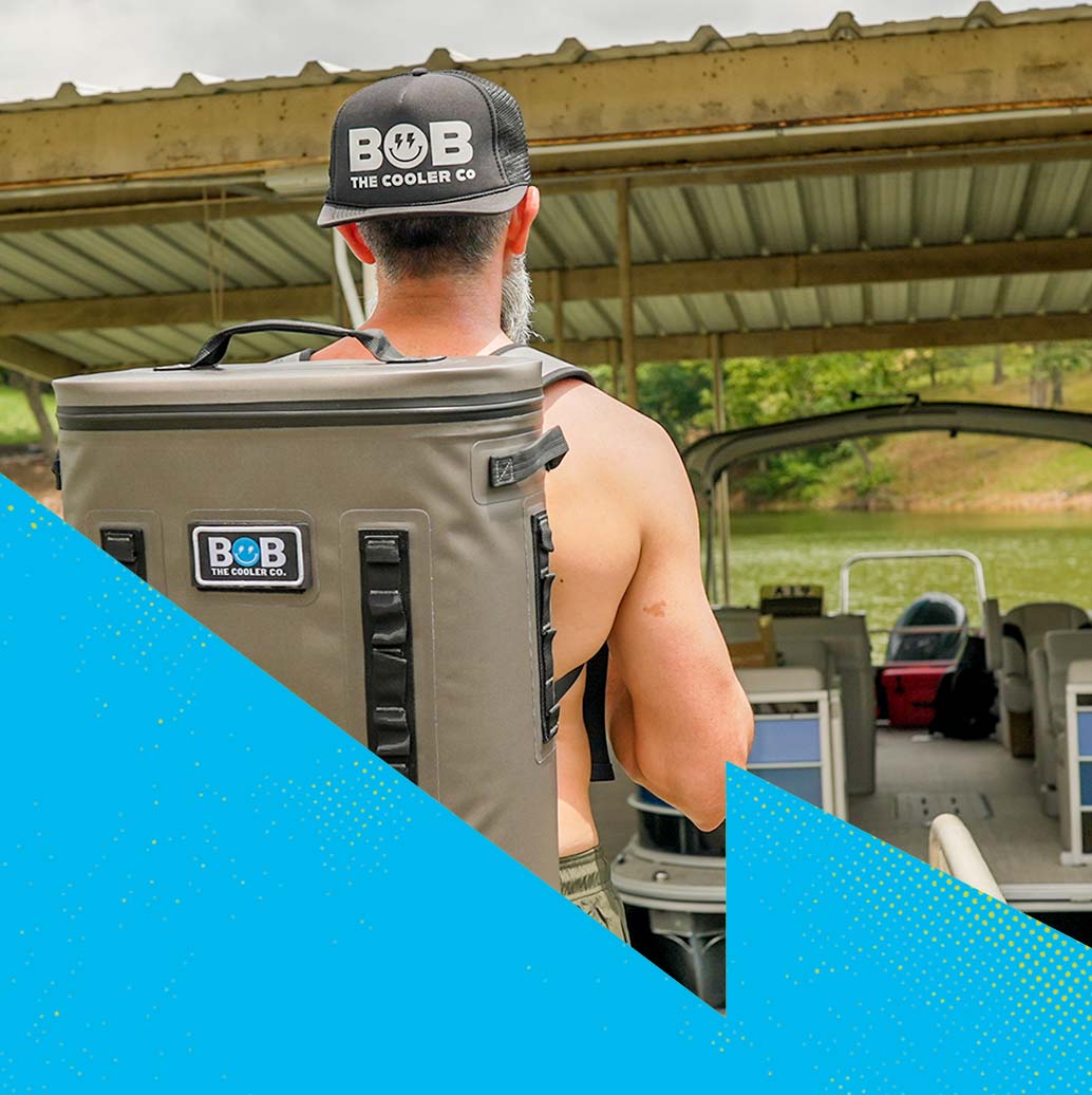 A man carrying a soft cooler backpack on his back while walking along a dock.