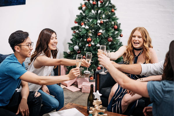 Friends toasting with champagne by a Christmas tree.