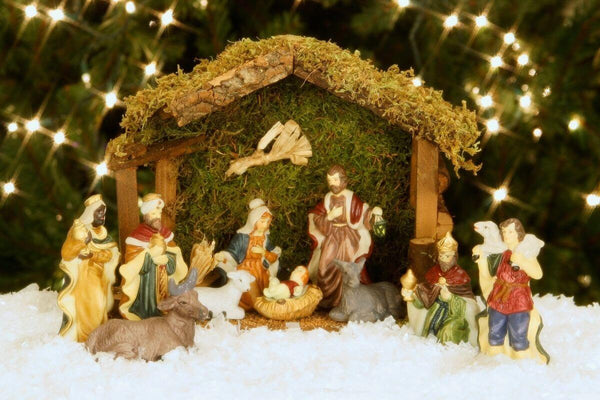 Nativity scene with figures and twinkling lights.