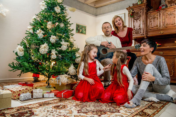 Family with children singing by the Christmas tree.