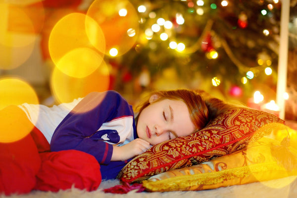 Child napping by the glow of Christmas tree lights