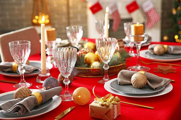 Festive table setting with candles and a red tablecloth.
