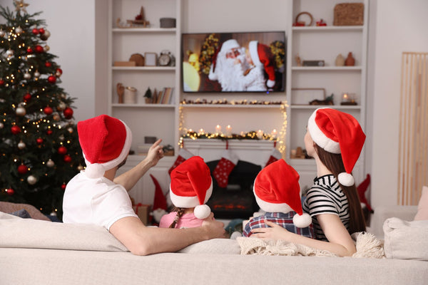 Family watching TV in Santa hats on Christmas.