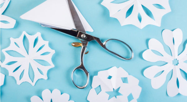 Snowflakes crafted from paper with scissors on a blue background.