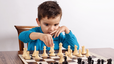 barn i blå tröja gör ett schack drag