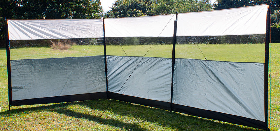 A windbreak pitched in a field, with a window panel running the full length