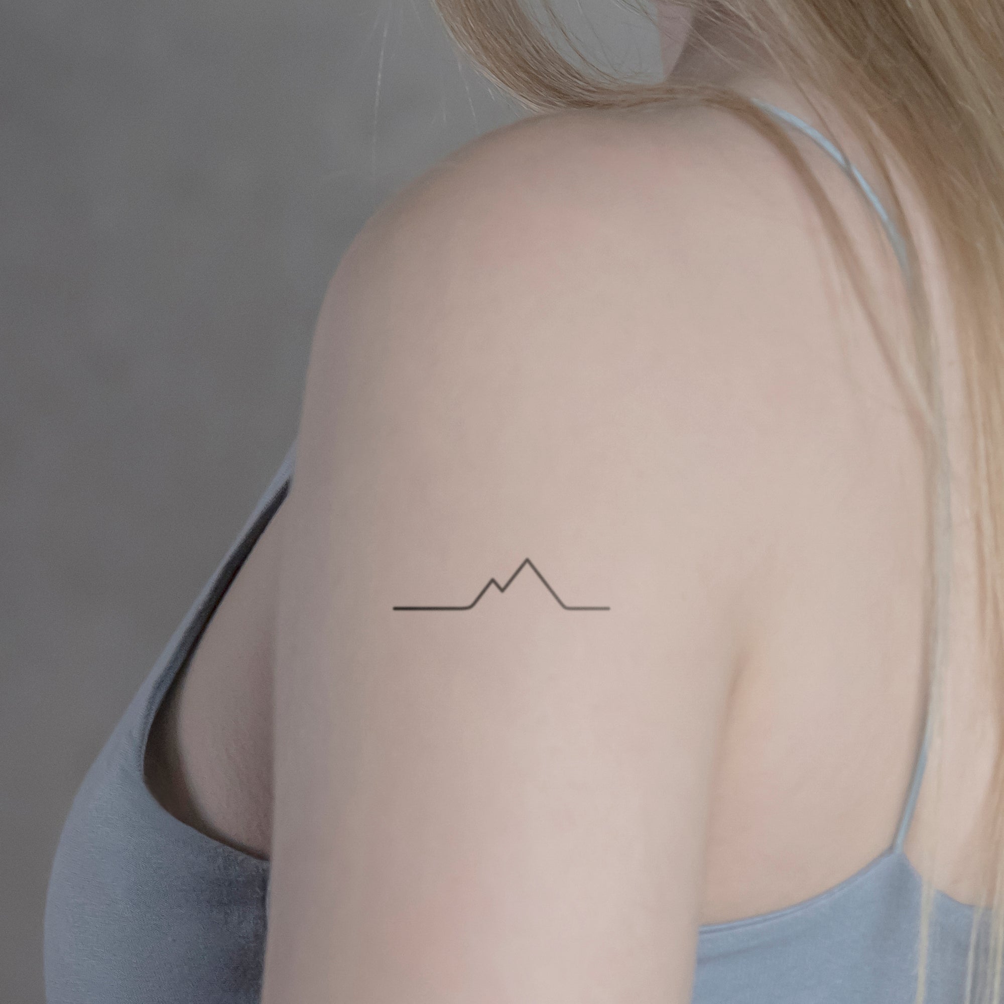 Mountain tattoo on the back of the right arm.