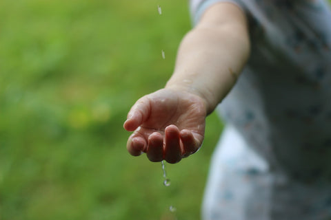Rainwater dripping on someones hand symbolizing sustainability