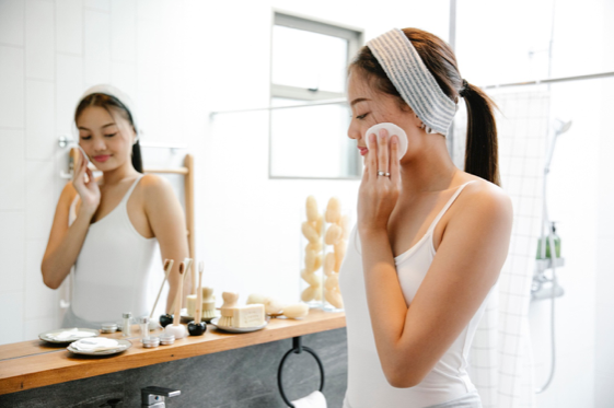 Une jeune femme est dans sa salle de bain en train de faire sa routine de peau. Il y a un jeu avec le miroir où l’on voit son visage de face alors que le premier plan on l’a voit de profil.