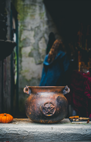 a woman walking away from a large cauldron