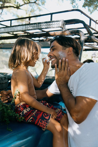 Un niño aplicando barrera solar a su papa