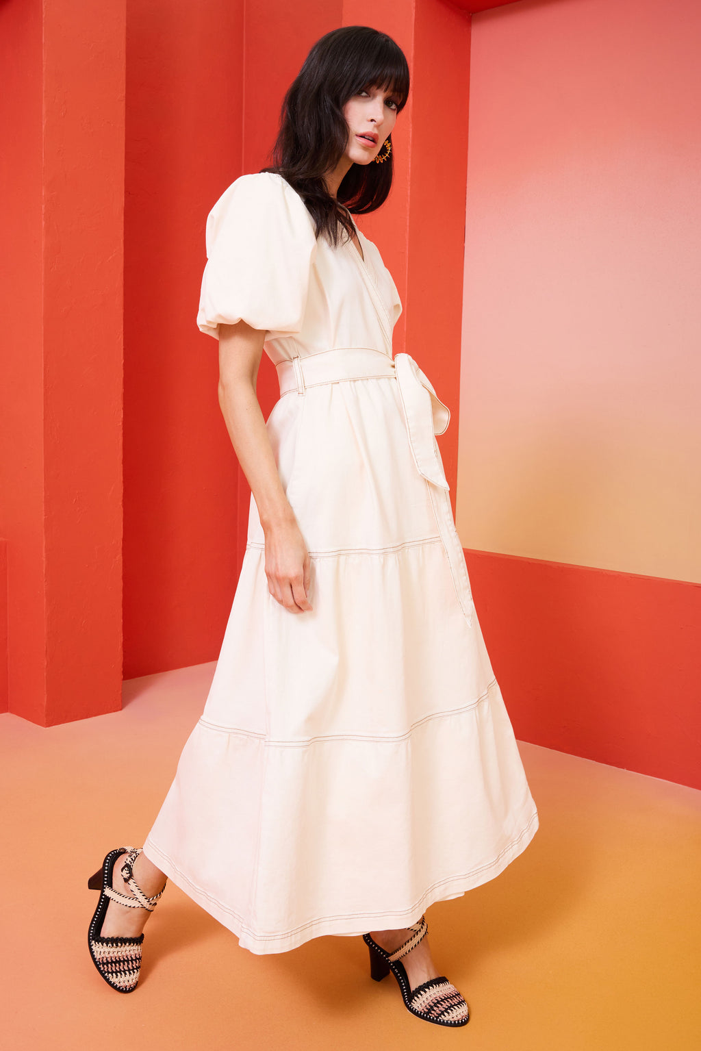 Long dress in an off white color and denim fabric that has short puff sleeves and a long tiered waist