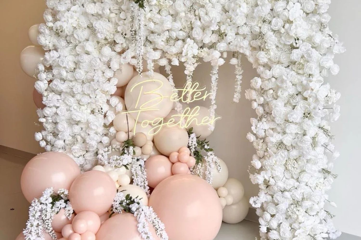 White flower arch with balloons.