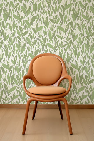 Vintage chair on a backdrop wall of Lily Valley green wallpaper designed by Kate Golding.