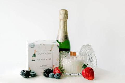 Avenue Aroma Champagne Candles Displayed with a bottle od champagne and fresh fruit