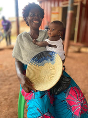 Ugandan artisan with hand woven basket and baby