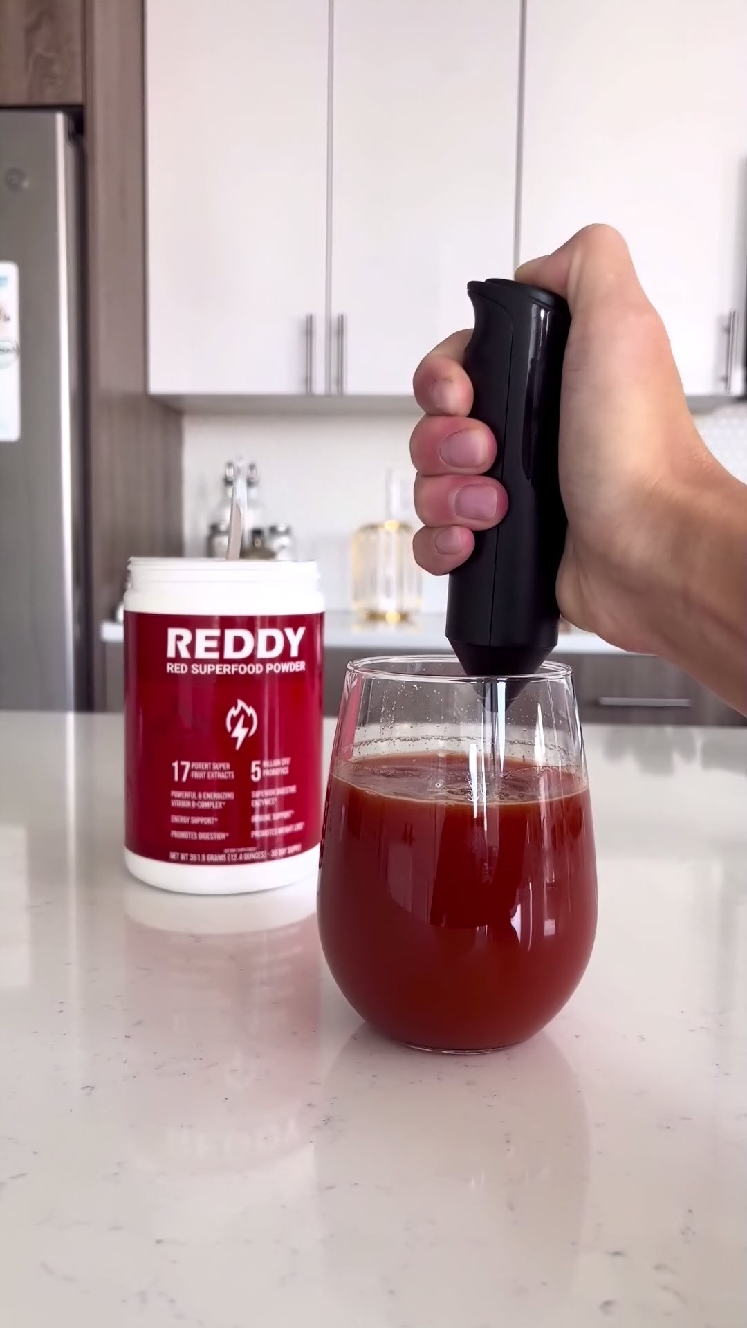 Hand mixer in a cup as it blend Reddy Red Superfood Powder into a cup of warm water