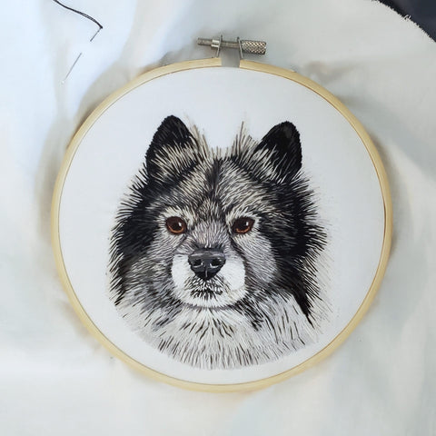 An embeoidered portrait of a keeshond dog
