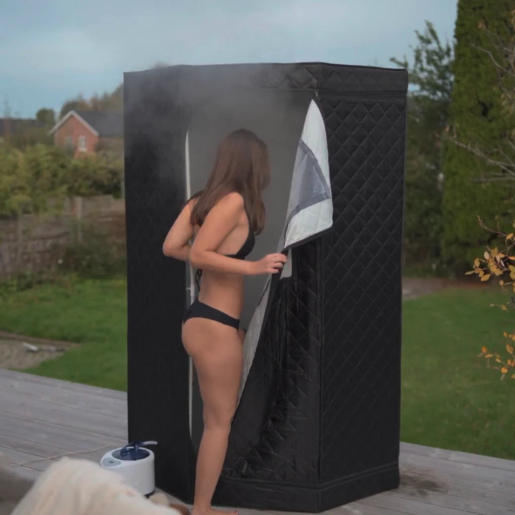 Woman entering a portable steam sauna outdoors.