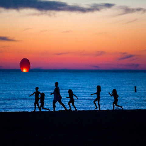 Canadian Family at the beach ad looking at a flying lantern going away in the sky