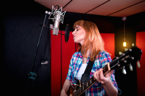 female singer with electric guitar recording a song