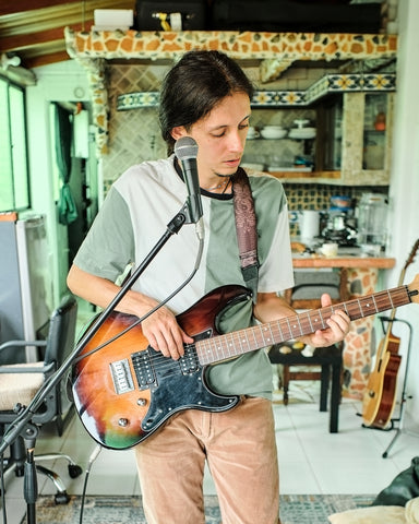 musician standing in the living room playing a guitar