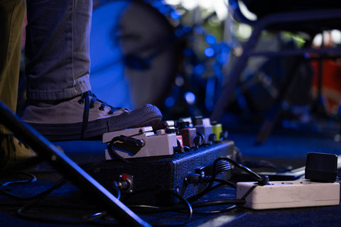 musician using guitar effects pedal during live performance